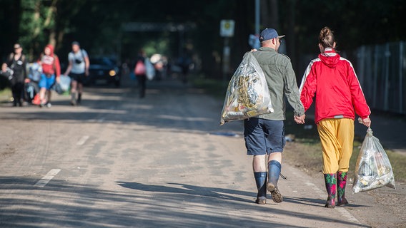 Zwei Menschen gehen it Müllsäcken eine Straße entlang. © dpa-Bildfunk 