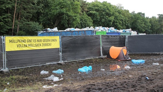 Eine Absperrwand mit  der Aufschrift "Pfand gibt es nur gegen einen vollen Müllsack zurück!" © NDR Foto: Adrian Lange