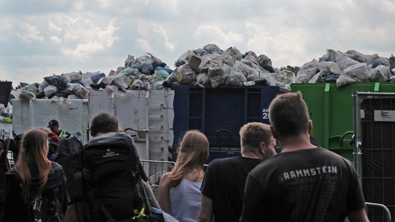 Festivalbesucher stehen vor überfüllten Müllcontainern. © NDR Foto: Adrian Lange
