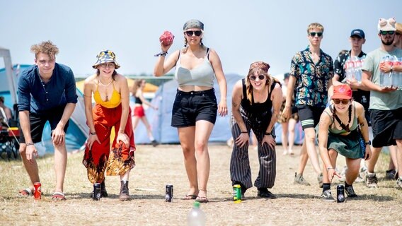Fünf Festival-Besucher stehen in einer Reihe und spielen ein Spiel. Im Hintergrund schauen andere Personen zu. © Hauke-Christian Dittrich/dpa Foto: Hauke-Christian Dittrich