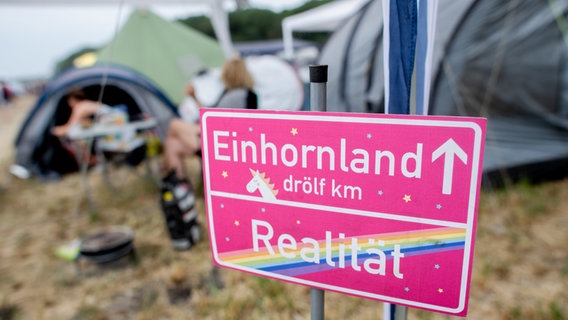 Ein Schild mit der Aufschrift "Einhornland" steht vor einem Zelt auf dem Zeltplatz des Hurricane Festivals. © dpa-Bildfunk Foto: Hauke-Christian Dittrich