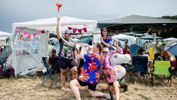 Shirley trinkt auf dem Zeltplatz des Hurricane Festivals Bier aus einem Trichter, während ihre Freundinnen Sophie (l-r), Janina und Levke sie anfeuern. © dpa-Bildfunk Foto: Hauke-Christian Dittrich