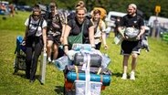 Festivalbesucher kommen zum Start des Hurricane Festival mit ihrem Gepäck am Zeltplatz an. © dpa Foto: Moritz Frankenberg