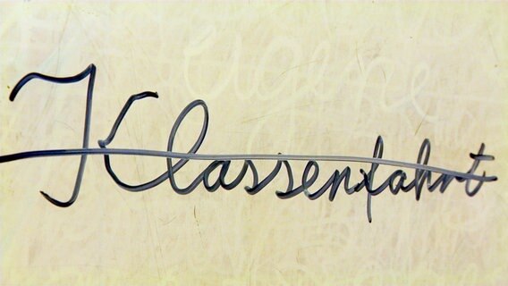The word class trip is crossed out on a board.  © NDR 