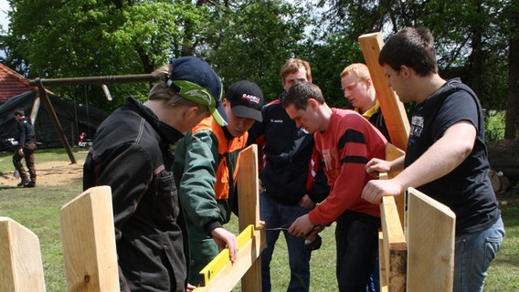 Eine Gruppe junger Männer vermisst Holzlatten.  
