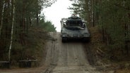 Ein Panzer fährt einen Hügel runter. © NDR 