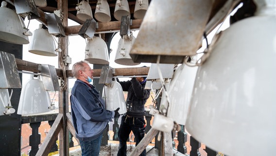 Glockenmonteure befestigen eine Porzellanglocke im Glockenspiel auf dem Dach des Rathauses. Die 41 Porzellanglocken erklingen nach einem guten Jahr Pause wieder mit je einem Lied. © dpa Bildfunk Foto: Philipp Schulze/dpa