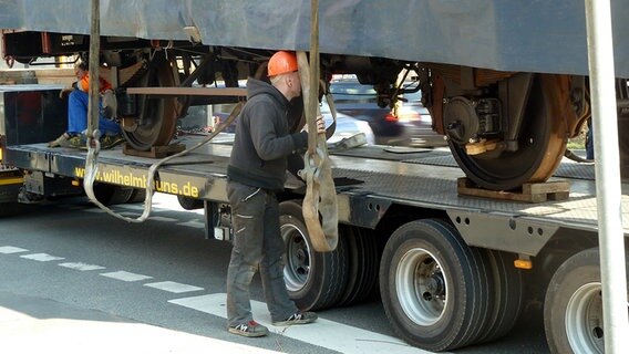 Ein Mann begutachtet einen Güterwagen der auf dem Auflieger eines Schwertransporters steht. © NDR Foto: Karin Hansen