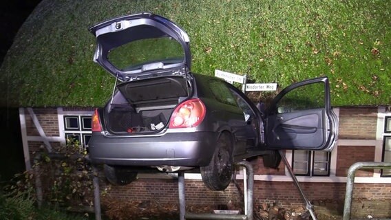 Ein Auto hängt in der Außenwand eines Reetdachhauses. © TV Elbnews 