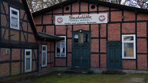 Auf einem Schild an einem alten Fachwerkhaus in Ostenholz steht: "Gaststätte 'Onkel Nickel' kalte und warme Speisen". © NDR 