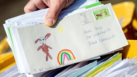 Eine Hand hält einen Brief mit gemaltem Ostehasen und Regenbogen. © dpa-Bildfunk Foto: Hauke-Christian Dittrich