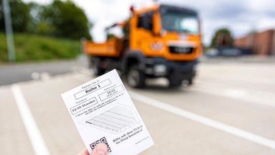 Eine Hand hält ein Parkticket vom neuen automatischen Kolonnen-Parksystem für Lastwagen auf dem Gelände von «Rosi's Autohof Dorfmark» an der Autobahn 7 im Landkreis Heidekreis. © Moritz Frankenberg/dpa Foto: Moritz Frankenberg