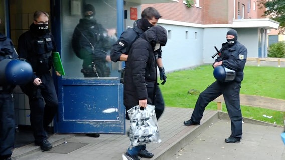 Ein Mann wird von einem maskierten Polizisten abgeführt © NEWS5 