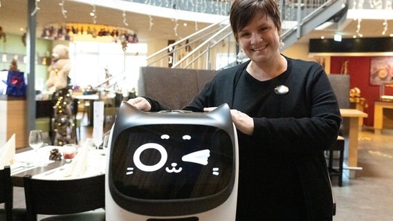 Deike Eder, Geschäftsführerin vom Anders Hotel Walsrode, steht neben dem Gastroroboter "Paula". © dpa-Bildfunk Foto: Swen Pförtner