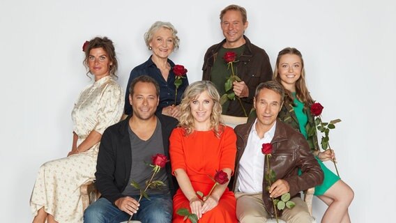 Die Schauspieler Anne Brendler (l-r), Daniel Hartwig, Edelgard Hansen, Nicole Ernst, Oliver Clemens, Stefan Plepp und Leonie Beuthner sitzen bei einem Fototermin zu den neuen Hauptfiguren der 19. Staffel "Rote Rosen" auf einem Sofa. © dpa-Bildfunk Foto: Georg Wendt