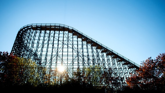 Die Sonne scheint durch das Gerüst der Holzachterbahn "Colossos" steht im Heide-Park. © dpa-Bildfunk Foto: Hauke-Christian Dittrich