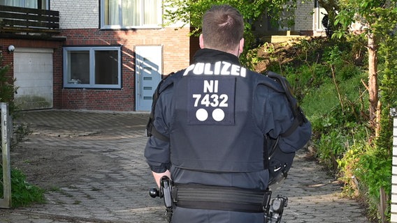 Ein Polizist steht vor einem Haus in Buchholz. © Polizeiinspektion Stade 