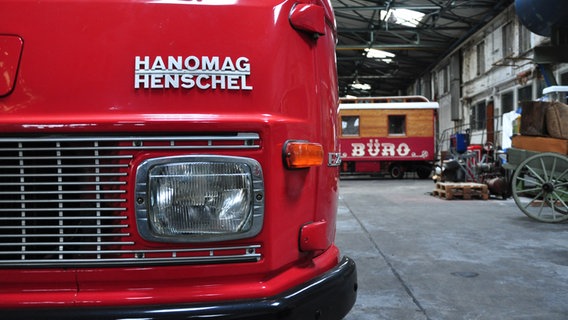 Im Vordergrund steht ein Feuerwehrauto von Hanomag Henschel. Im Hintergrund ist ein alter Wohnwagen mit der Aufschrift: "Büro" zu sehen. © NDR Foto: Thomas Hans