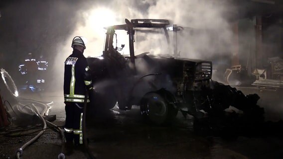 Einsatzkräfte der Feuerwehr löschen einen Traktor. © TV-Elbnews 
