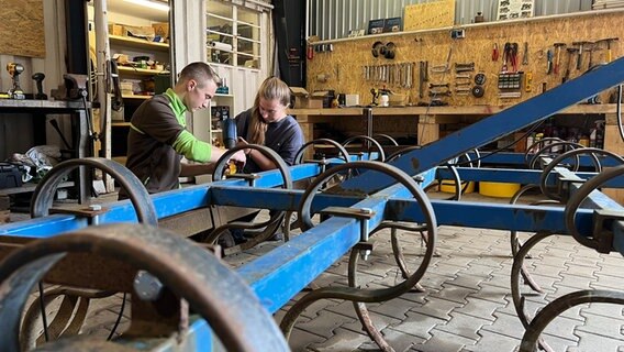 Timo Tobaben und Ciara Engelken reparieren einen Traktor. © NDR Foto: Marlene Kukral