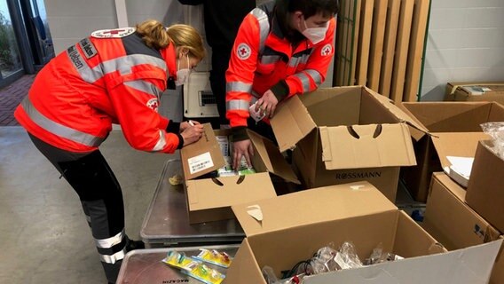 Mitarbeitende des DRK packen Kartons ein. © NDR Foto: Björn Ahrend