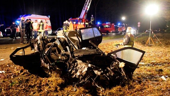 Ein völlig zerstörter VW Golf nach einem Unfall. Im Hintergrund stehen mehrere Feuerwehrautos. © dpa Foto: Daniel Bockwoldt
