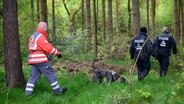 Einsatzkräfte des Roten Kreuzes sind mit einem Suchhund in einem Waldstück in Bremervörde im Einsatz, um einen vermissten Jungen zu finden. © Daniel Reinhardt / dpa Foto: Daniel Reinhardt
