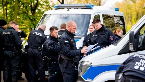 Polizisten stehen vor Polizeibullis und bereiten sich auf die Suche nach Arian vor. © dpa-Bildfunk/ Daniel Bockwoldt Foto: Daniel Bockwoldt