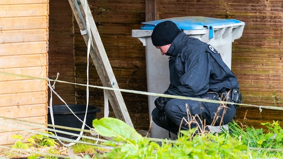 Gräpel: Ein Polizist sucht in einem Tierstall bei der Suche nach einem vermissten Jungen nach Spuren am Boden.  © dpa-Bildfunk Foto: Daniel Bockwoldt