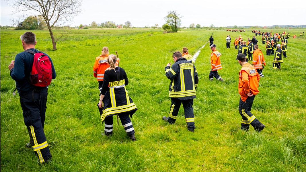 Feuerwehrleute suchen mit einer Menschenkette auf einem Feld nach dem vermissten Jungen Arian aus Bremervörde.
