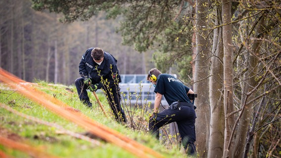 Einsatzkräfte der Polizei suchen in der Nähe der A7 mit einem Metalldetektor nach Beweismitteln. © dpa-Bildfunk Foto: Moritz Frankenberg