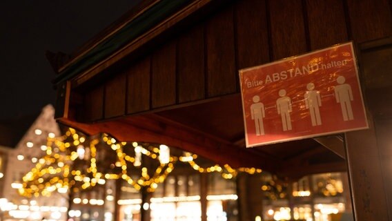 "Bitte Abstand halten" steht an einer Weihnachtsmarkt-Bude auf dem Marktplatz. © dpa Foto: Philipp Schulze