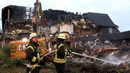 Die Feuerwehrleute und ein Bagger bei der Brandruine eines Wohnkomplexes für Geflüchtete in Wittorf. © TV Elbnews 