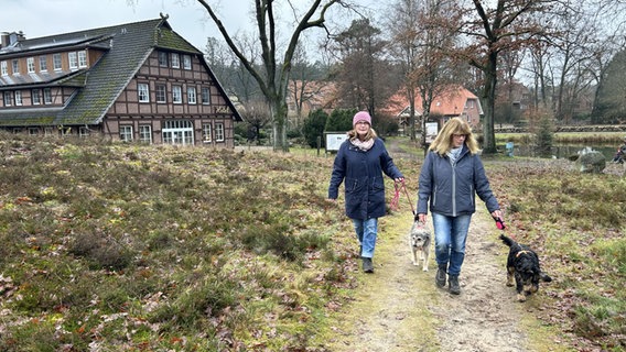 Sabine Wolff (li) geht mit ihrer Schwester Andrea Wolff spazieren. Beide haben einen angeleinten Hund an ihrer Seite. © NDR Foto: Marie Schiller