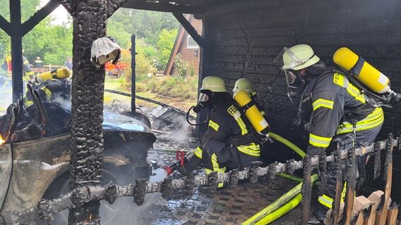 Einsatzkräfte der Feuerwehr löschen einen Carport-Brand. © Kreisfeuerwehr Lüchow-Dannenberg 