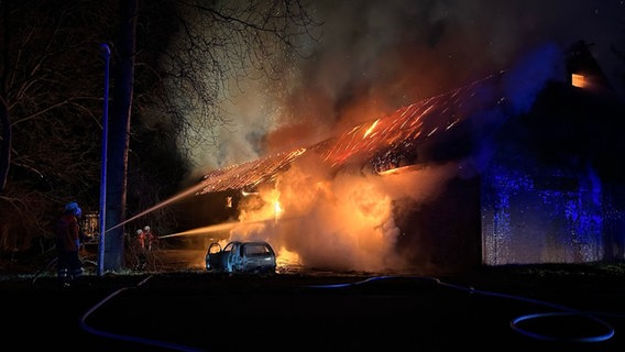 Ein Auto steht nach einem Unfall vor einer brennenden Scheune in Zeven. © Kreisfeuerwehr Rotenburg (Wümme) 