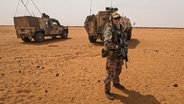 Der Soldat Tim M. steht in Mali vor Bundeswehrfahrzeugen. © NDR 