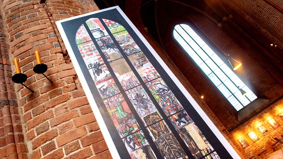 Ein Abbild des von Markus Lüpertz entworfenen Kirchenfensters zum Thema Reformation steht während eines Ortstermins im Zivilprozess um das Fenster in der Marktkirche. © picture alliance/dpa/Hauke-Christian Dittrich Foto: Hauke-Christian Dittrich