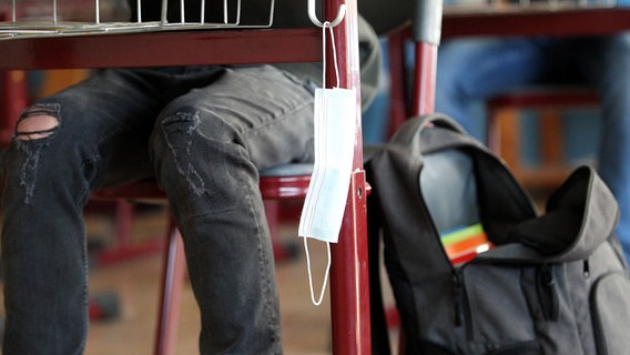 Eine medizinische Maske hängt in einem Klassenzimmer an einem Pult. © picture alliance/Eibner-Pressefoto/Fleig Foto: Fleig