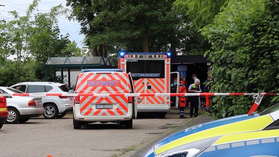 Notarzt und Polizei stehen auf einem Parkplatz. Bei einem Angriff mit einem Messer ist ein 55-Jähriger in Lienen (Kreis Steinfurt) am Mittwochabend getötet worden. © Nord-West-Media TV 