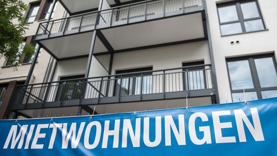 Vor einem mehrstöckigen Wohnhaus hängt ein Banner mit der Aufschrift "Mietwohnungen". © dpa-Bildfunk Foto: Silas Stein