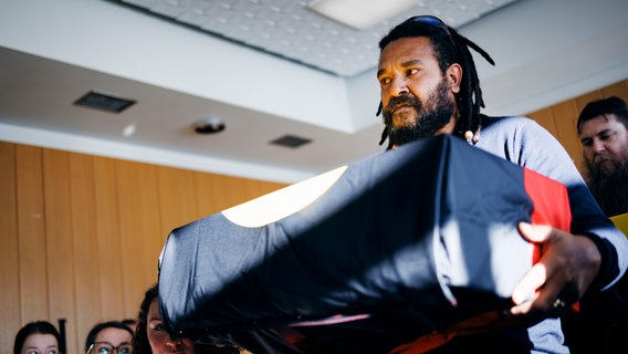 Ein Mann hat trägt die australischen Ahnen in den Händen. Sie wurden bei einer Zeremonie in Berlin zurück an Australien gegeben. © Stiftung Preußischer Kulturbesitz Foto: Felix Zahn