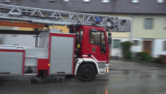 Ein Feuerwehrauto fährt eine Straße entlang. © NDR 