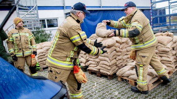 Feuerwehrleute werfen sich in Oldenburg einen Sandsack zu. © dpa - Bildfunk Foto: Hauke-Christian Dittrich