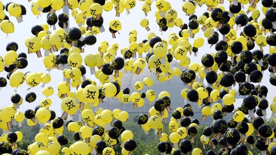 Schwarze und gelbe Luftballons steigen vor dem Atomkraftwerk Unterweser in Kleinensiel in den Himmel. © NDR.de Foto: Ingo Wagner