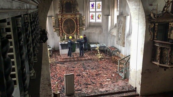Polizisten fotografieren einen Altar in einer Kirche nach einem Brand.  