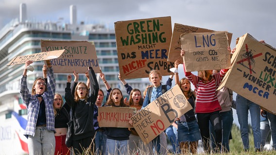 Zahlreiche junge Menschen demonstrieren an der Meyer Werft, wo das Kreuzfahrtschiff ·Arvia· aus dem Dock bugsiert wird, gegen den ·Luxus auf dem Meer· und "green-washing" in der Kreuzfahrtbranche. © dpa-bildfunk Foto: Lars Klemmer/dpa