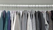 Kleidungsstücke hängen an Bügeln in einem Schrank. © NDR Foto: Oliver Gressieker