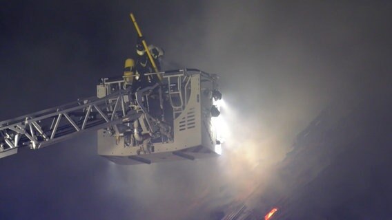 Eine Einsatzkraft der Feuerwehr löscht einen Hausbrand von einer Drehleiter aus. © NonstopNews 