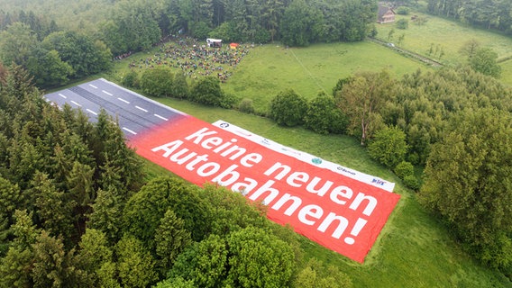 Ein Banner mit der Aufschrift "Keine neuen Autobahnen" liegt auf einer Wiese. © Picture Alliance Foto: Mohssen Assanimoghaddam